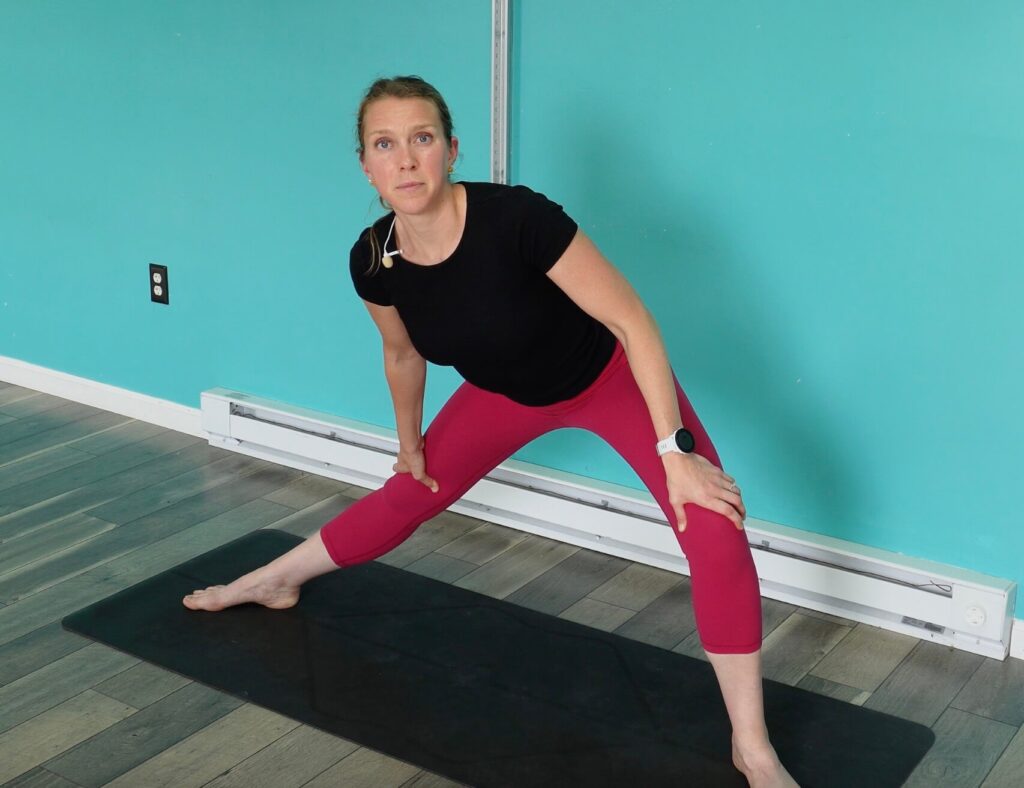 With legs wider than hip width apart, Dr. Chloe has one leg straight and the other knee bent and stretching through the inner thigh of the straight leg for improving running form